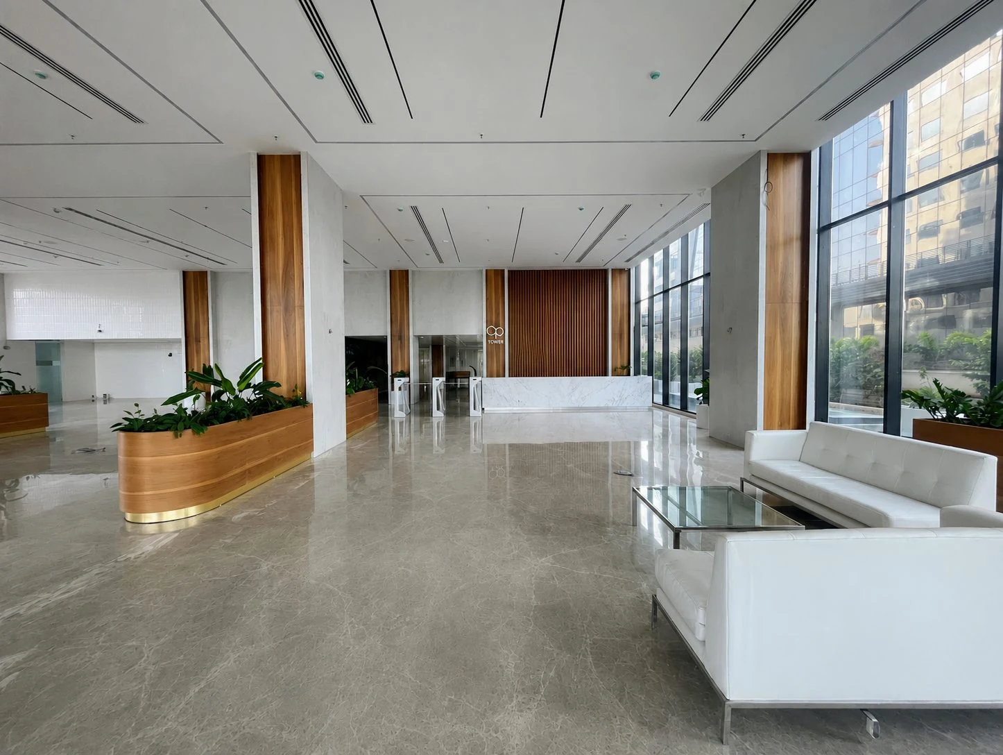 Main reception and arrival at OP Tower with white marble, timber columns, planting and full-height glazing